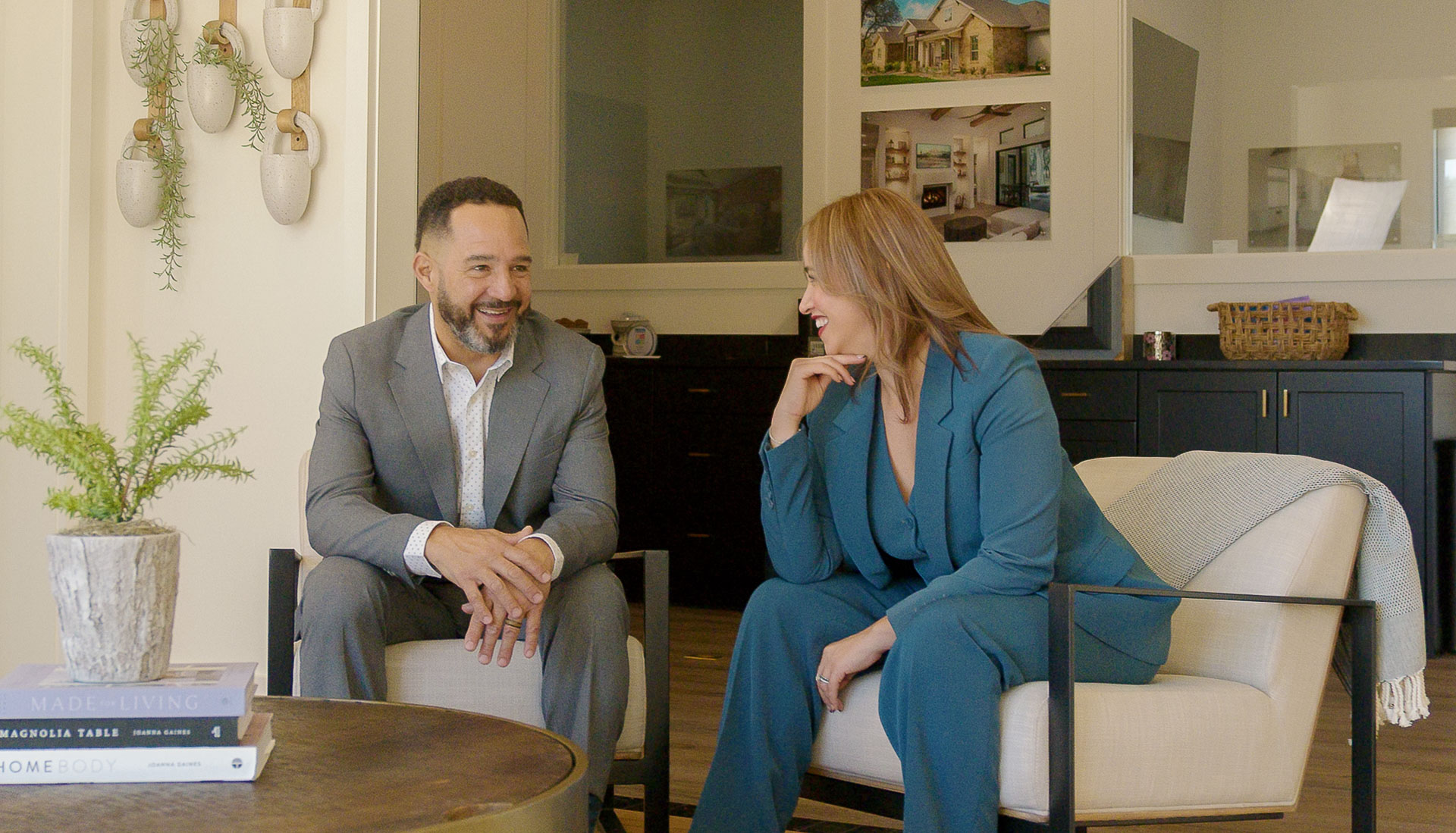 Katherine and Cesar Laboy, co-founders of Domum Realty, talking and laughing together in a bright, modern Austin living room